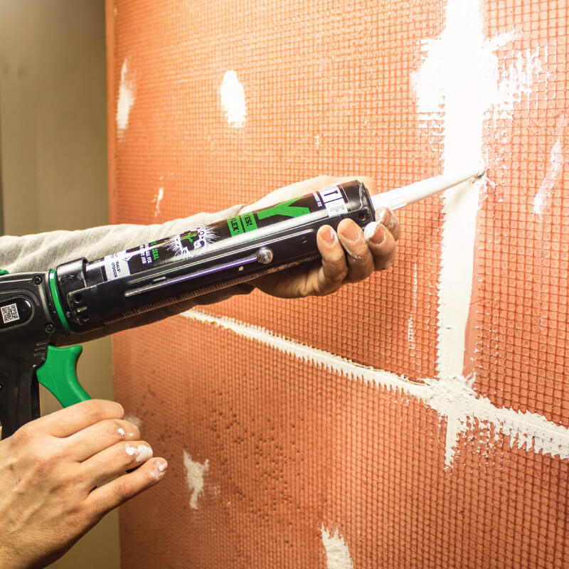 man using adhesive sealant on wall